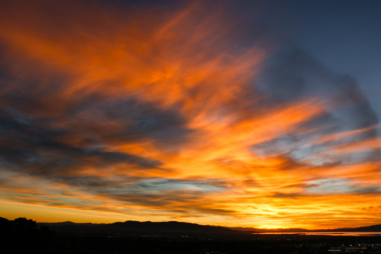 golden clouds seem to rise in a giant arch in the sky over mountains and a town